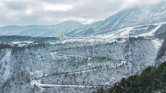 成都摄影照片_空中无人俯瞰西岭雪山,四川滑雪场紧邻成都.山路蜿蜒穿过树林、滑雪场和旅游基地。冬季体育活动.