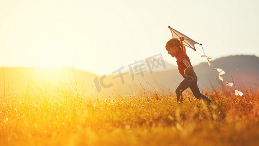 风筝摄影照片_快乐的小女孩，夏天带着风筝在草地上奔跑