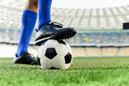 足球腿摄影照片_足球场上穿着蓝色袜子和足球鞋的职业足球运动员的腿