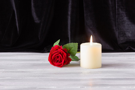 纪念、葬礼和哀悼的概念。黑色背景上的烛光和红玫瑰，有文字的自由空间