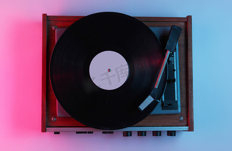 流行风格摄影照片_复古风格的音乐概念。带有渐变粉色蓝色霓虹灯的Vinyl唱机。流行文化。80年代.