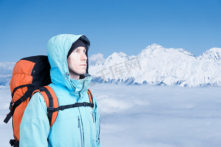 登山人看起来在高峰期，站在反对一个冬天多雪的山风景.