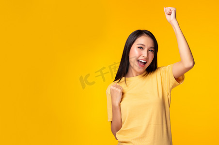 快乐兴奋的年轻亚洲女人高举双手庆祝成功形象快乐的亚洲女人举起拳头微笑着面对迷人的女孩快乐，享受生活黄色背景的复制空间