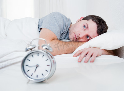 男人在床上用眼睛打开遭受失眠和睡眠障碍