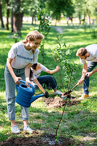 青年志愿者在公园里植树和浇灌新树 