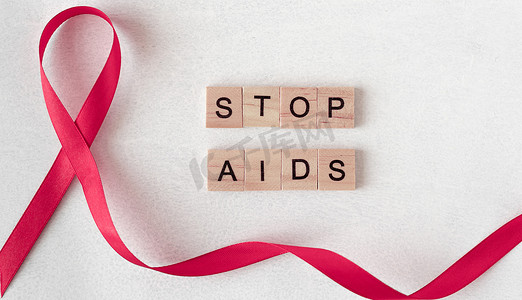 艾滋病日摄影照片_世界艾滋病日的概念。木制字母旁边的红丝带。班纳，复制空间。制止艾滋病