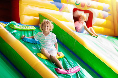 幼儿城堡摄影照片_孩子跳上五颜六色的操场蹦床。孩子们跳在充气弹跳城堡在幼儿园的生日聚会活动和游乐中心的幼儿。夏天在户外玩耍的小男孩.
