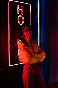 sign摄影照片_young asian woman in sunglasses standing with crossed arms near red neon hotel sign 