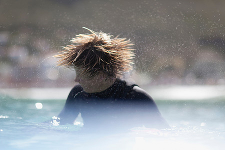 少年冲浪者摇着他的头发