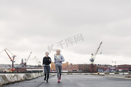 两位女性跑步朋友沿着码头跑步