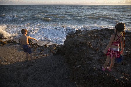 男孩和妹妹指着海滩上的海浪吹石保护区美国佛罗里达州朱庇特岛