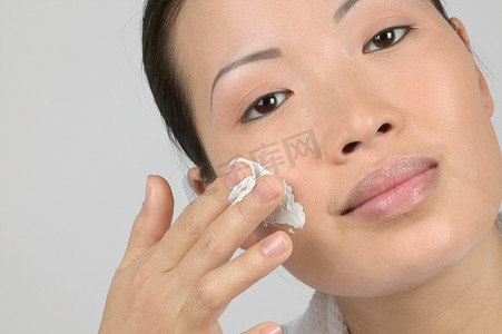 女性将保湿霜涂在脸颊上