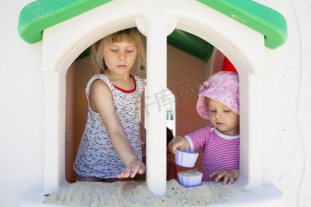 女幼儿和妹妹在游乐场的窗台上玩沙子