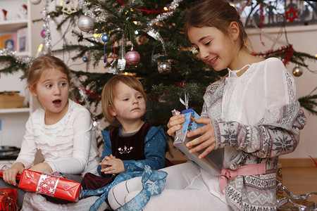 女孩们在圣诞树前打开礼物