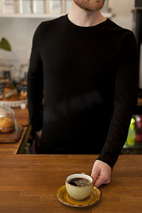 剪影咖啡杯摄影照片_咖啡馆服务员端上新鲜咖啡的剪影
