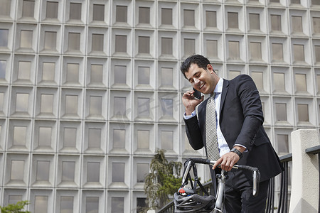 中年商务人士手持自行车用智能手机打电话