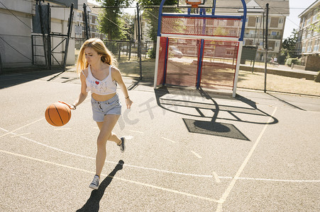 年轻女子在篮球场上带着球奔跑