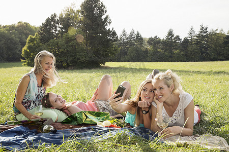 躺在草地上的妇女用智能手机微笑自拍