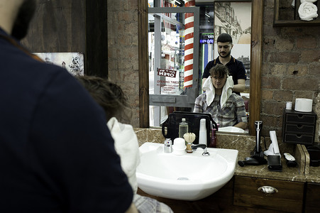 入口牌子摄影照片_理发店里年轻人和理发师的镜像
