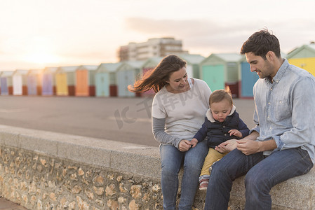 克莱因蓝水波底纹摄影照片_坐在海滩墙上的年轻家庭