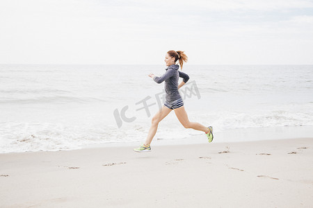一名中年妇女沿着海滩奔跑