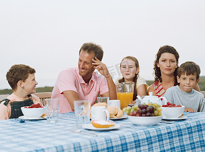 少女盘坐摄影照片_在户外吃早餐的家庭