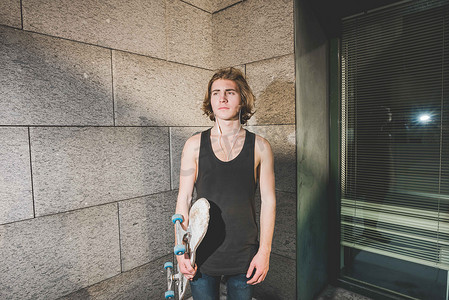 z在线摄影照片_城市年轻男子滑板运动员手持滑板站着的肖像