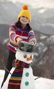 十几岁的女孩给雪人戴上帽子