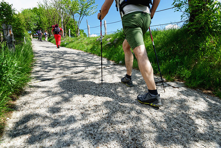 前进团队摄影照片_在乡村公路上徒步旅行的成年男女徒步旅行者的背影