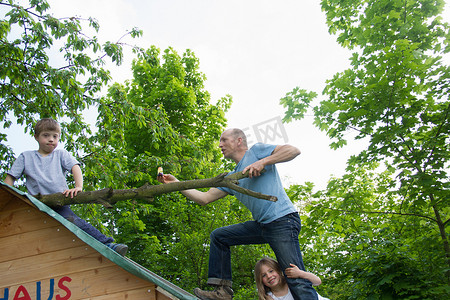 父亲和两个孩子在玩具屋屋顶上爬