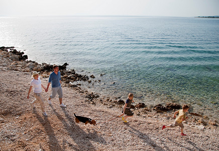 一家人带着狗在海滩上跑步