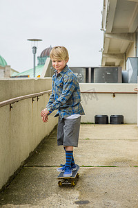 滑板坡道摄影照片_男孩滑板滑下停车场坡道