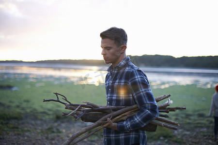 日落时分一个背着海上漂流木头的年轻人