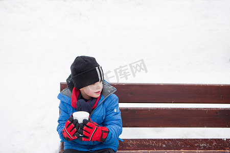 安全带帽摄影照片_在寒冷的日子里喝着热饮的男孩