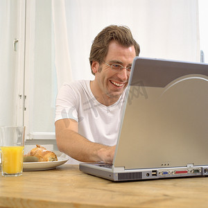 早餐时拿着笔记本电脑的男人