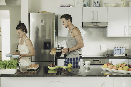 咖啡壶摄影照片_年轻夫妇从厨房柜台端着早餐