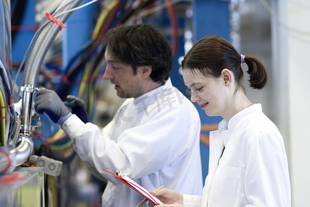 男同事和女同事穿着实验室大衣拿着剪贴板的侧视