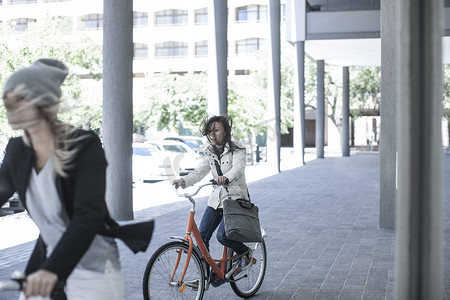 两位头发飘逸的女性朋友在城市骑自行车