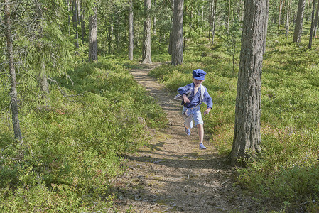 穿着复古服装的男孩在森林中奔跑