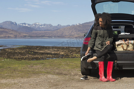 苏格兰赫布里底斯斯凯岛艾肖特湖坐在汽车后备箱上穿鞋的中年妇女