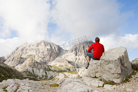 山峰的人摄影照片_坐在岩石上看山峰的人