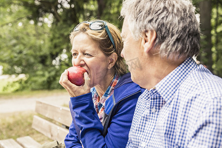 一对夫妇坐在户外成熟的女人吃着苹果
