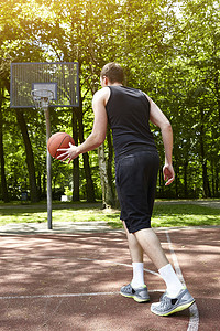 年轻男子篮球运动员在球场上带球奔跑的背影