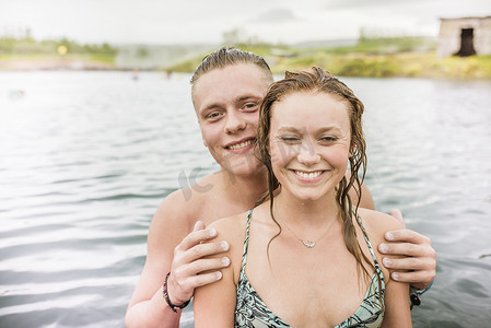 微笑的年轻夫妇站在冰岛福夫迪尔的秘密泻湖温泉里
