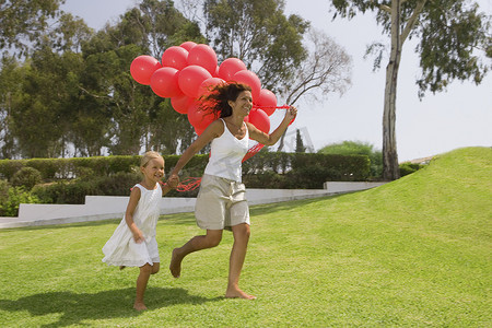 孩子和母亲摄影照片_带着气球跑步的女孩和母亲