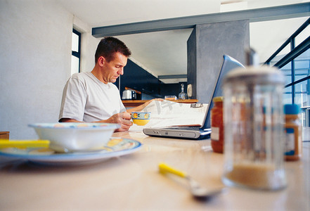 迈特凯摄影照片_男人在早餐时使用笔记本电脑