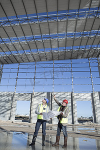 两个人抬头看摄影照片_测量师和建筑师抬头看着建筑框架