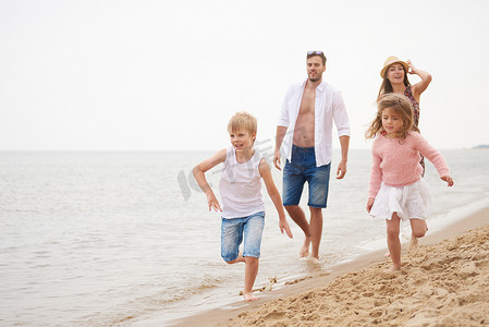 爱情阶段摄影照片_一家人在沙滩上跑步