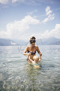 民族图案及摄影照片_意大利伦巴第卢伊诺母亲在齐腰深的湖中牵着儿子的手的前景