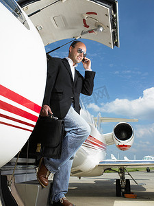 飞机侧视图摄影照片_一名休闲商人走出私人飞机